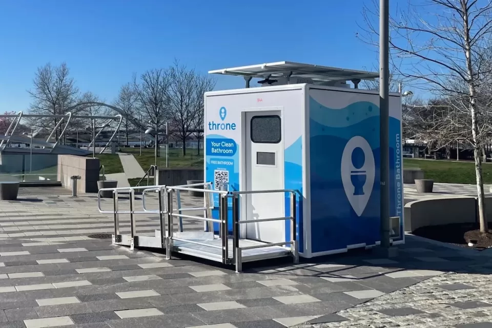 Blue and white Throne portable bathroom in an outdoor location.